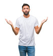 © Krakenimages.com - Adult hispanic man over isolated background clueless and confused expression with arms and hands raised. Doubt concept.