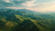 Aerial view of lush mountain range with sunlit peaks and valleys