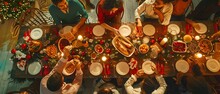 An Assortment Of Family Members And Friends Gathered Around A Dining Room Table, Sharing Food, Conversing, Creating A Joyful Holiday Atmosphere. Top Down View.
