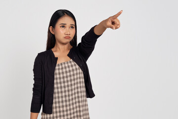 Beautiful young Asian woman wearing casual shirt pointing finger at copy space with annoyed expression isolated on white background. People lifestyle concept