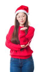 Wall Mural - Young Chinese woman over isolated background wearing christmas hat looking at the camera blowing a kiss with hand on air being lovely and sexy. Love expression.