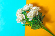White roses bouquet on yellow and blue background. Flat lay.