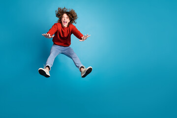 Sticker - Full length photo of cheerful positive guy dressed red pullover jumping high emtpy space isolated blue color background