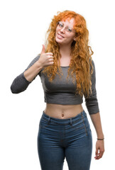 Sticker - Young redhead woman doing happy thumbs up gesture with hand. Approving expression looking at the camera with showing success.