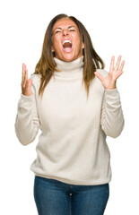 Wall Mural - Beautiful middle age adult woman wearing winter sweater over isolated background crazy and mad shouting and yelling with aggressive expression and arms raised. Frustration concept.