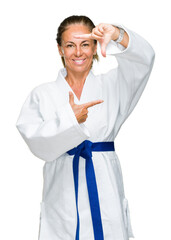 Poster - Middle age adult woman wearing karate kimono uniform over isolated background smiling making frame with hands and fingers with happy face. Creativity and photography concept.