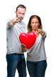 © Krakenimages.com - Middle age hispanic casual couple in love holding red heart over isolated background pointing with finger to the camera and to you, hand sign, positive and confident gesture from the front