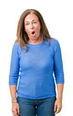Wall Mural - Middle age beautiful woman wearing winter sweater over isolated background In shock face, looking skeptical and sarcastic, surprised with open mouth