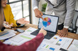 © Wasana - A group of people are looking at a pie chart on a laptop. The man pointing at the chart is explaining something to the others