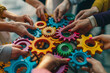 © ink drop - Close up of a team of business people holding colorful gears in their hands working together
