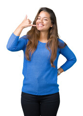 Sticker - Young beautiful brunette woman wearing blue sweater over isolated background smiling doing phone gesture with hand and fingers like talking on the telephone. Communicating concepts.