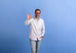 Portrait of handsome entrepreneur showing OK sign and laughing ecstatically over blue background