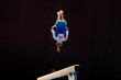 woman exercise on balance beam gymnastics, perform backward somersault on black background