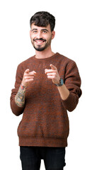 Wall Mural - Young handsome man wearing winter sweater over isolated background pointing fingers to camera with happy and funny face. Good energy and vibes.