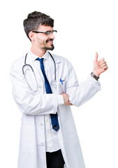 Wall Mural - Young doctor man wearing hospital coat over isolated background Looking proud, smiling doing thumbs up gesture to the side