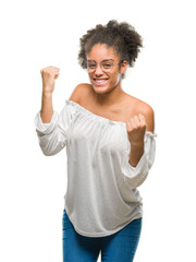 Canvas Print - Young afro american woman wearing glasses over isolated background very happy and excited doing winner gesture with arms raised, smiling and screaming for success. Celebration concept.