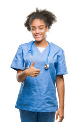 Wall Mural - Young afro american doctor woman over isolated background doing happy thumbs up gesture with hand. Approving expression looking at the camera with showing success.