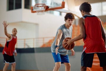 College students playing basketball at indoor court.