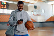 © Drazen - Happy black athlete texting on cell phone after basketball practice.