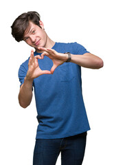 Wall Mural - Young handsome man wearing blue t-shirt over isolated background smiling in love showing heart symbol and shape with hands. Romantic concept.