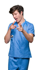 Wall Mural - Young doctor wearing medical uniform over isolated background pointing fingers to camera with happy and funny face. Good energy and vibes.