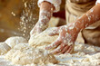 Worker in a bakery kneading dough with flour flying all around