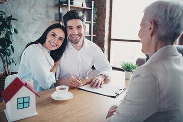 Wall Mural - Photo of young couple cuddle sign documents meeting realtor lady desk loft interior office indoors