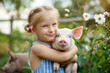 Adorable little girl playing with piglet outdoors