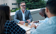 © peopleimages.com - Businesspeople, meeting and outside with smile at table on rooftop for brainstorming or collaboration. Teamwork, laugh and funny conversation for joke with colleagues in town in London with happiness