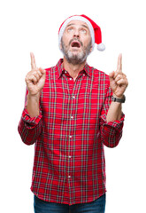 Wall Mural - Middle age hoary senior man wearing christmas hat over isolated background amazed and surprised looking up and pointing with fingers and raised arms.