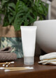 White cream tube near basin and green plant on wooden countertop in bath, mockup