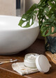 Opened cosmetic cream jar near basin and green plant on wooden countertop in bath, lid mockup
