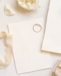 Cards with engagement ring, flowers and beige silk ribbon top view, copy space, wedding mockup