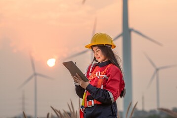 Woman engineer inspection posing check control wind power machine in wind energy factory at silhouette sunset. girl technician professional worker check wind power machine for maintenance turbine