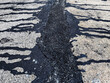 Asphalt on road. Street with black tar filling the cracks. Cracks in concrete surface are then filled with asphalt. Texture of old asphalt road. Asphalt is covered with cracks, which filled with tar.