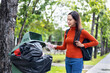 woman is throwing away trash and holding a bottle