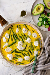 Wall Mural - Omelet with asparagus and goat cheese in a pan with avocado and green salad