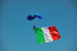 paratrooper with huge Italian flag on blue sky during National Alpini rally of Italian Military Corp