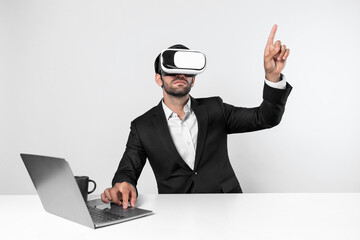 Skilled business man looking at data analysis while sitting at table with laptop and wearing VR glasses. Project manager working by using virtual reality system or connecting at metaverse. Deviation.