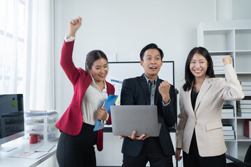 Wall Mural - Group of young business people discussing business while working by using line chart  and laptop in the office together 