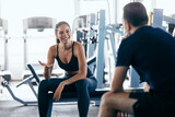 Fototapeta Pomosty - Focus on the smiling gym girl talking to her partner, resting from a workout.
