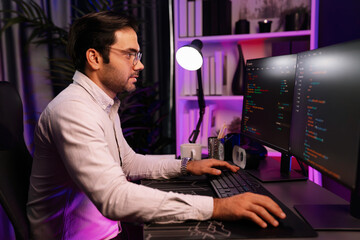 Working smart IT developer analyzing data software development on two pc screen, creating application program updated version online website page system online at neon light cyber office. Surmise.