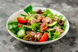 Salad with tuna, lettuce, cucumbers, tomatoes and olives in white plate