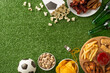 Group of snacks arranged on green turf for a football match viewing, including beers, peanuts, and fries