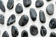 Pattern of black stones arranged on white background for relaxation, meditation and wellness concept