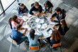 © Iftikhar alam - Group of students actively discussing while sitting around a round table, A group of students collaborating at a round table