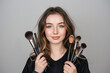 Woman holding set of makeup brushes on grey background