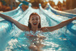 Cheerful woman rides down a slide in water park