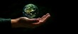 The hand hold a miniature glass Earth on a black background. Ecology concept. Earth Day.
