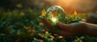The hands hold a miniature glass Earth on a green nature background. Ecology concept. Earth Day.